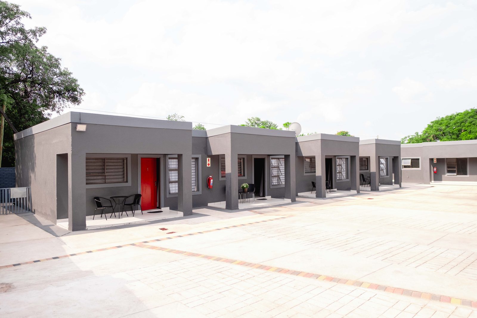 Viata Luxe exterior — grey cottages with red doors, paved courtyard